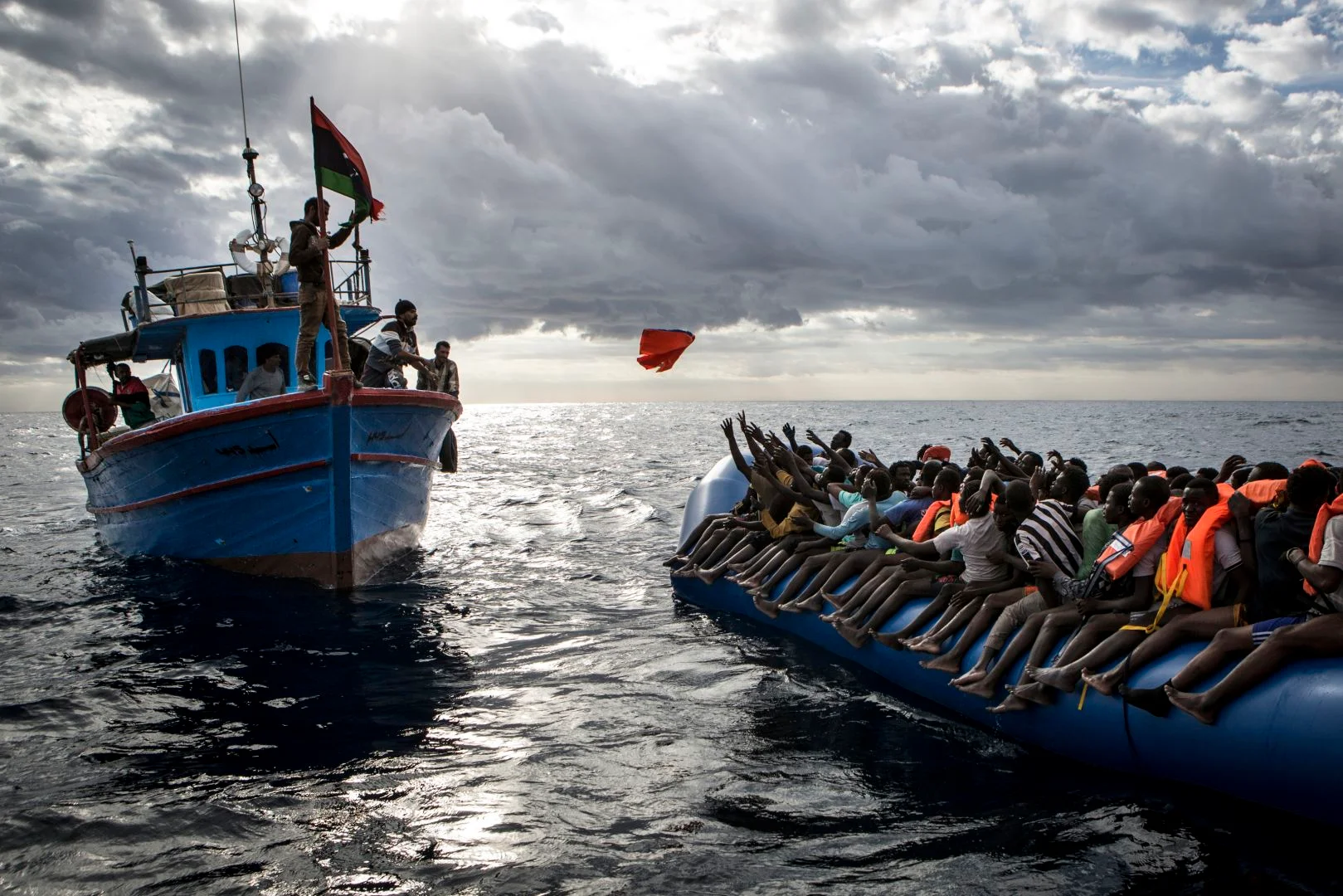 Pescadores libios arrojan un chaleco salvavidas a un bote de refugiados.
