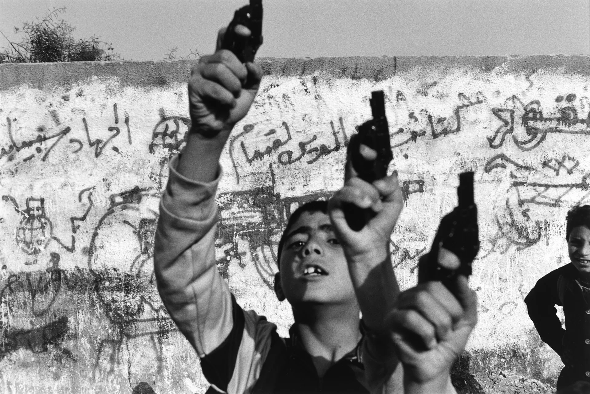 Niños palestinos levantan pistolas de juguete en un gesto de desafío.