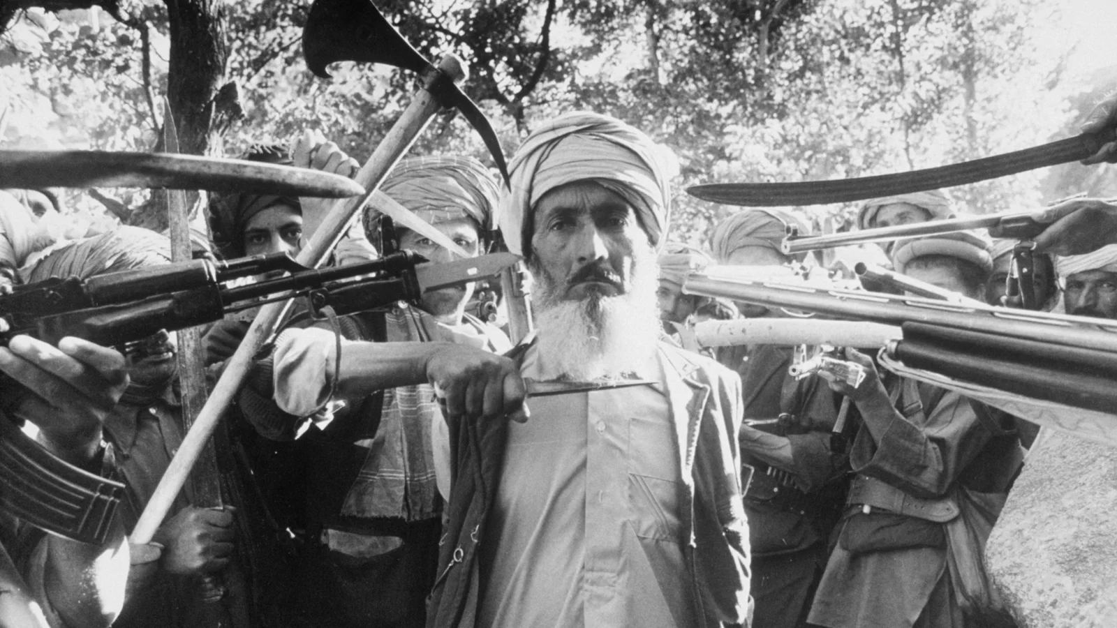 Convicted by an Islamic war court for denouncing nine families, a man is escorted 20 km from Kabul for execution.