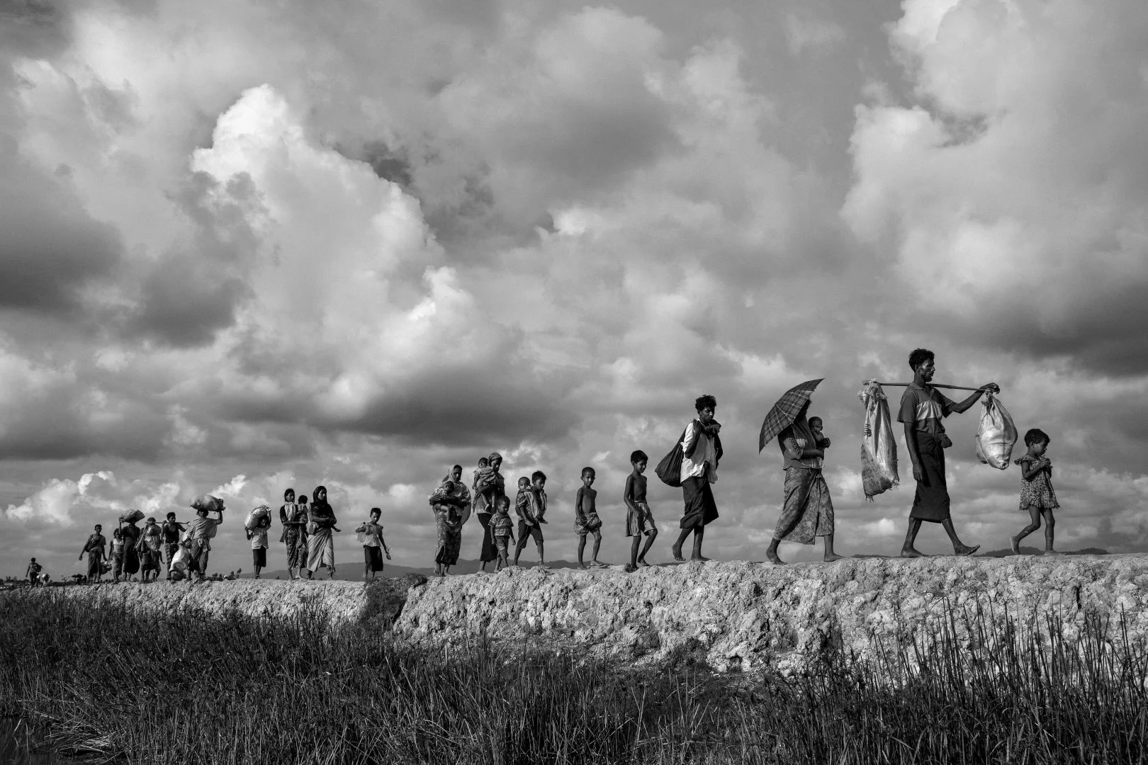 Refugiados rohingya llevan sus pertenencias mientras caminan por el lado de Bangladesh del río Naf después de huir de Myanmar.