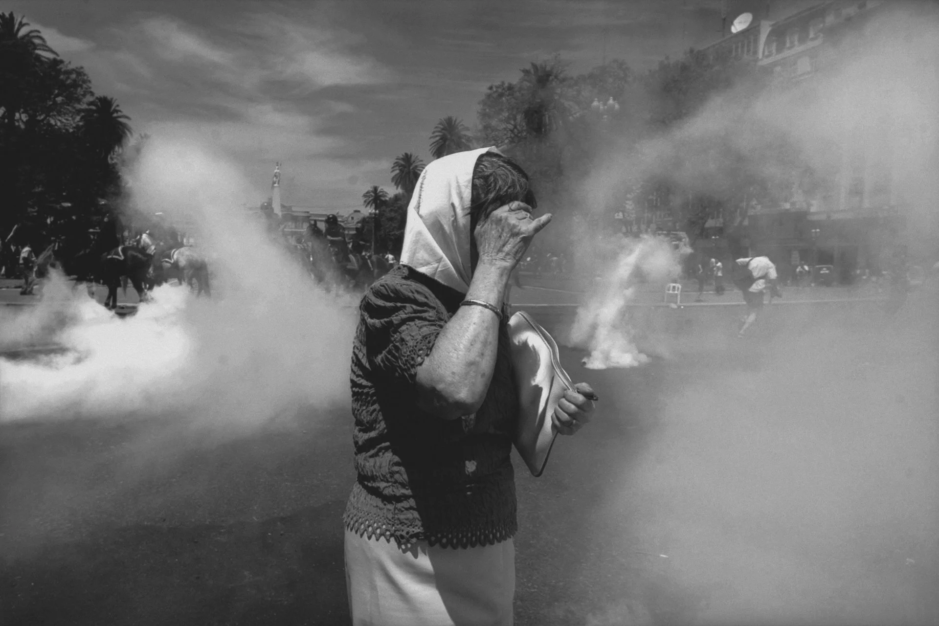 Uma mãe protege os olhos do gás lacrimogêneo durante protestos contra o desaparecimento de seus parentes e outras mães. Outros argentinos também protestavam contra a crise económica.