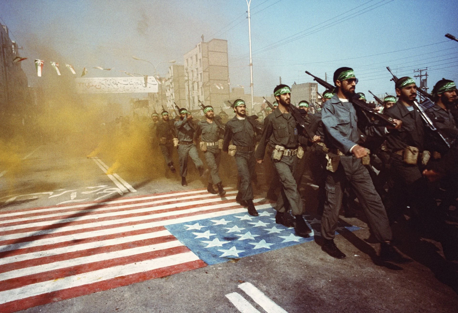 Soldados iraníes caminan sobre una bandera estadounidense.