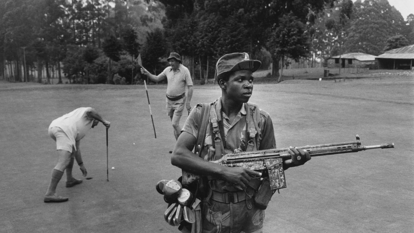 Вооруженный охранник обеспечивает обслуживание и безопасность белых родезийцев на поле для гольфа отеля Leopard Rock в горах Бвумба, Родезия.