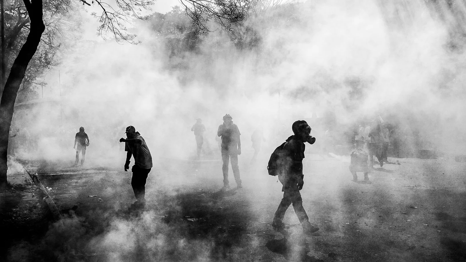 Manifestantes caminan a través de gases lacrimógenos durante protestas contra el gobierno.