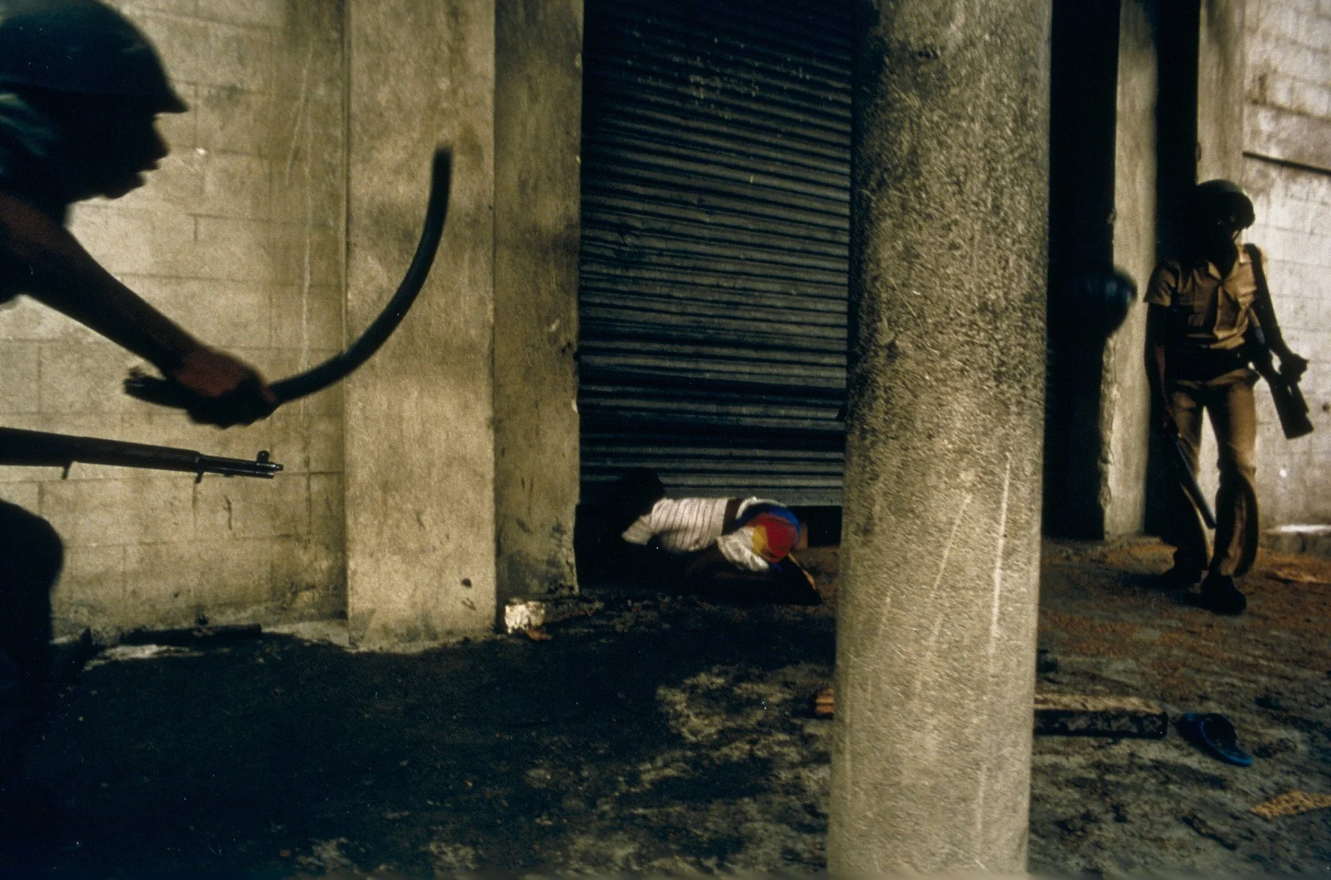 Los soldados se acercan a un niño pequeño que intenta recuperar una caja de alimentos de un depósito, durante los días turbulentos que llevaron a la caída del régimen de Duvalier en febrero de 1986.