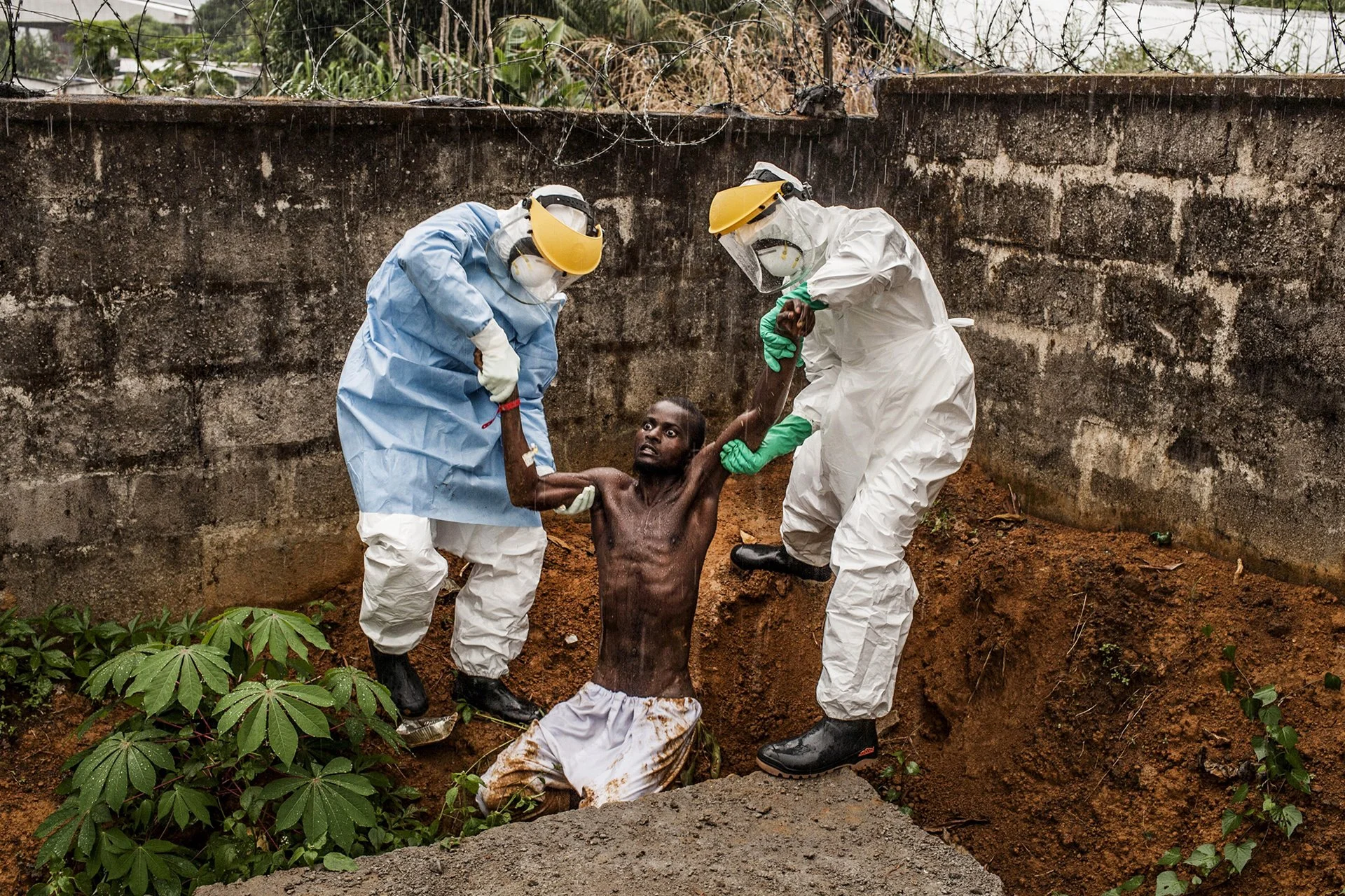 El personal médico escolta a un hombre, delirando en las etapas finales del ébola, de regreso a la sala de aislamiento de la que había escapado, en Hastings, cerca de la capital, Freetown.