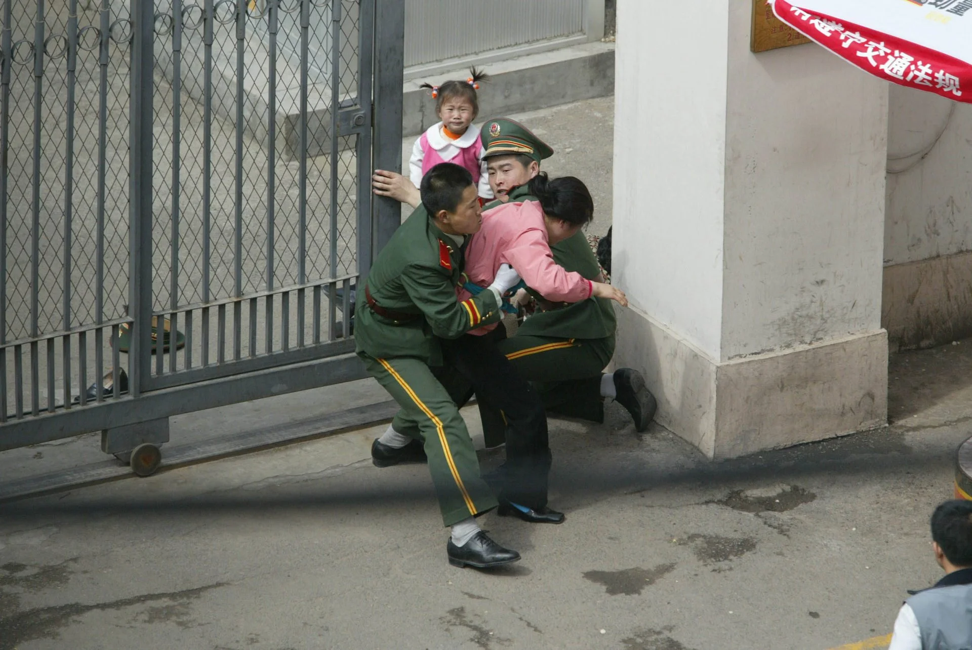La policía china forcejea con una mujer norcoreana en la puerta del consulado japonés, mientras su hija observa. 
