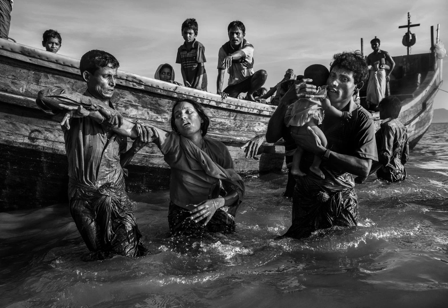 Una refugiada rohingya recibe ayuda desde un bote cuando llega a Shah Porir Dwip.