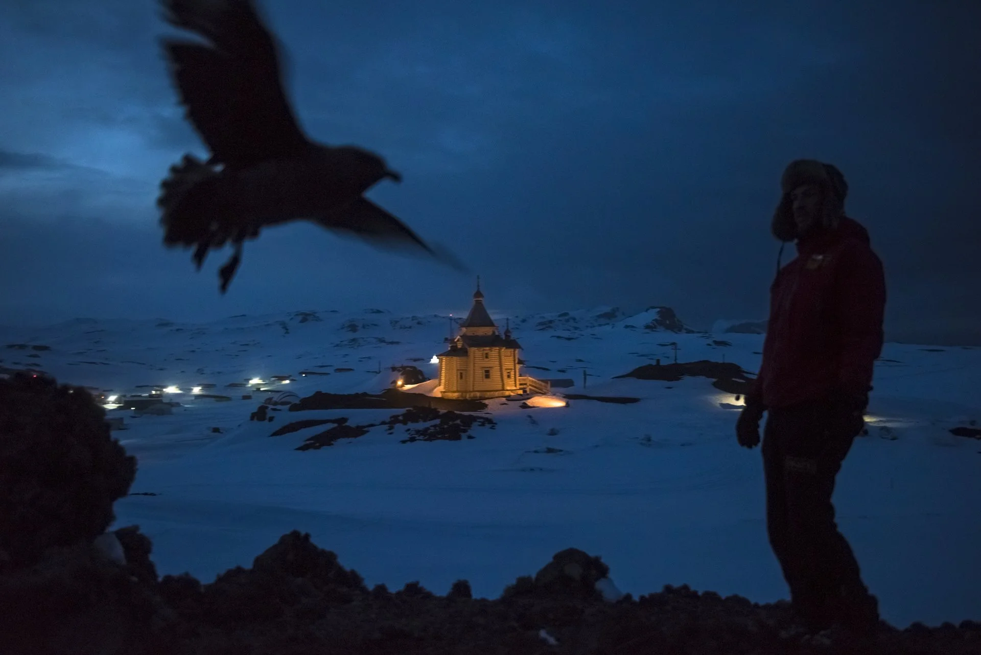 El Dr. Ernesto Molina, quien cuenta con el apoyo del Instituto Antártico Chileno, camina frente a la base antártica rusa de Bellingshausen, con su Iglesia Ortodoxa de la Santísima Trinidad.