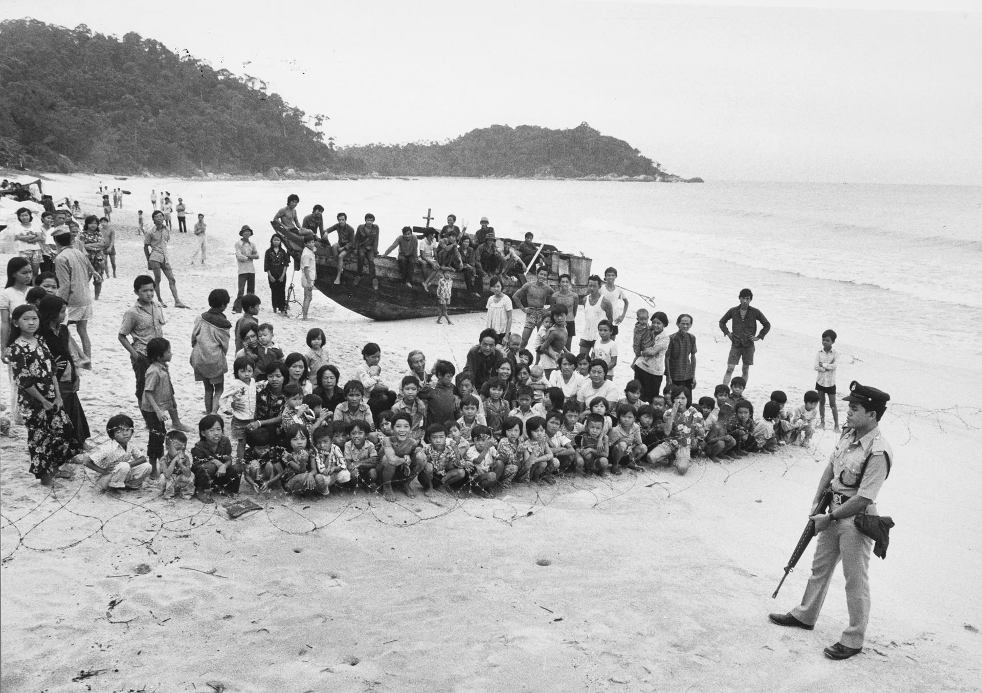 Varados en una playa de Tailandia a la que habían llegado varias semanas antes, estas personas son mantenidas detrás de alambre de púas y bajo vigilancia armada mientras esperan ser devueltas al mar.