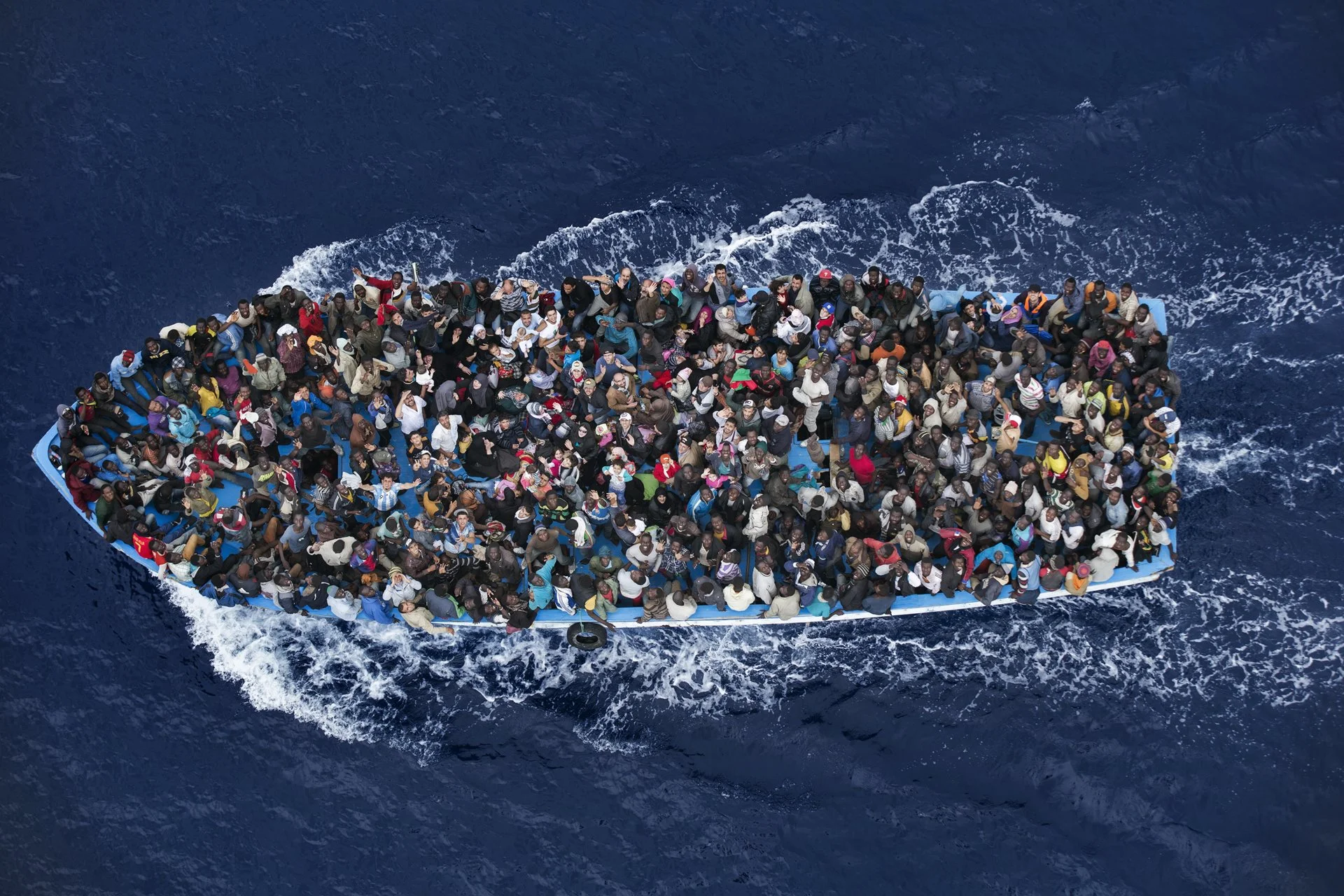 Refugiados se amontonan a bordo de un barco a unos 25 kilómetros de la costa de Libia, antes de ser rescatados por una fragata naval italiana que trabaja como parte de la Operación Mare Nostrum (OMN).