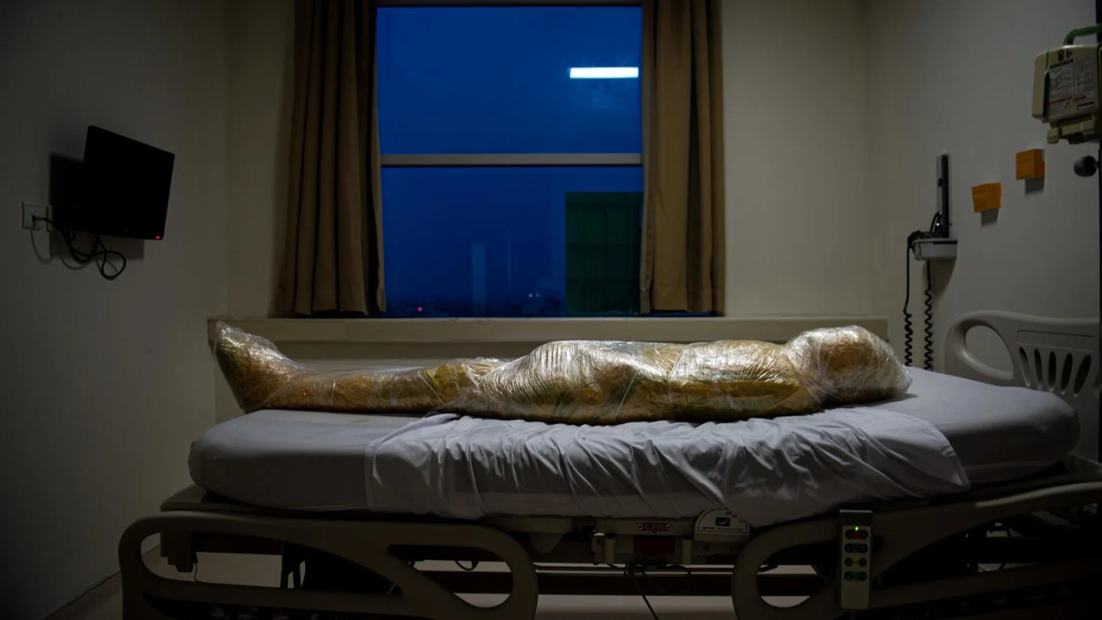 El cuerpo de una presunta víctima de coronavirus, envuelto en plástico amarillo, yace esperando una bolsa para cadáveres, en un hospital de Indonesia.