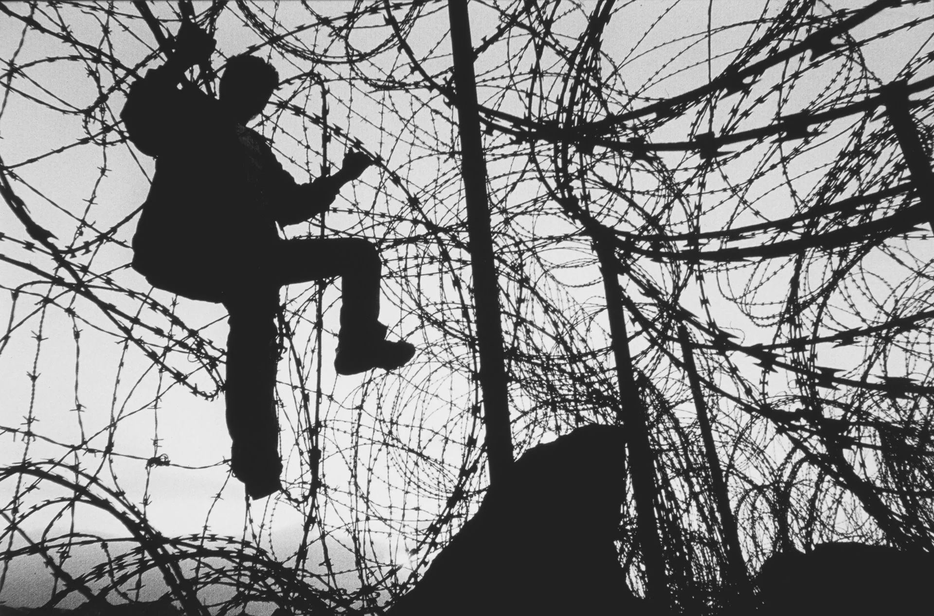 Un hombre sube una barrera para cruzar la frontera hacia Melilla o Ceuta, enclaves hermanos españoles en Marruecos, desde donde los inmigrantes esperan acceder a la España continental.
