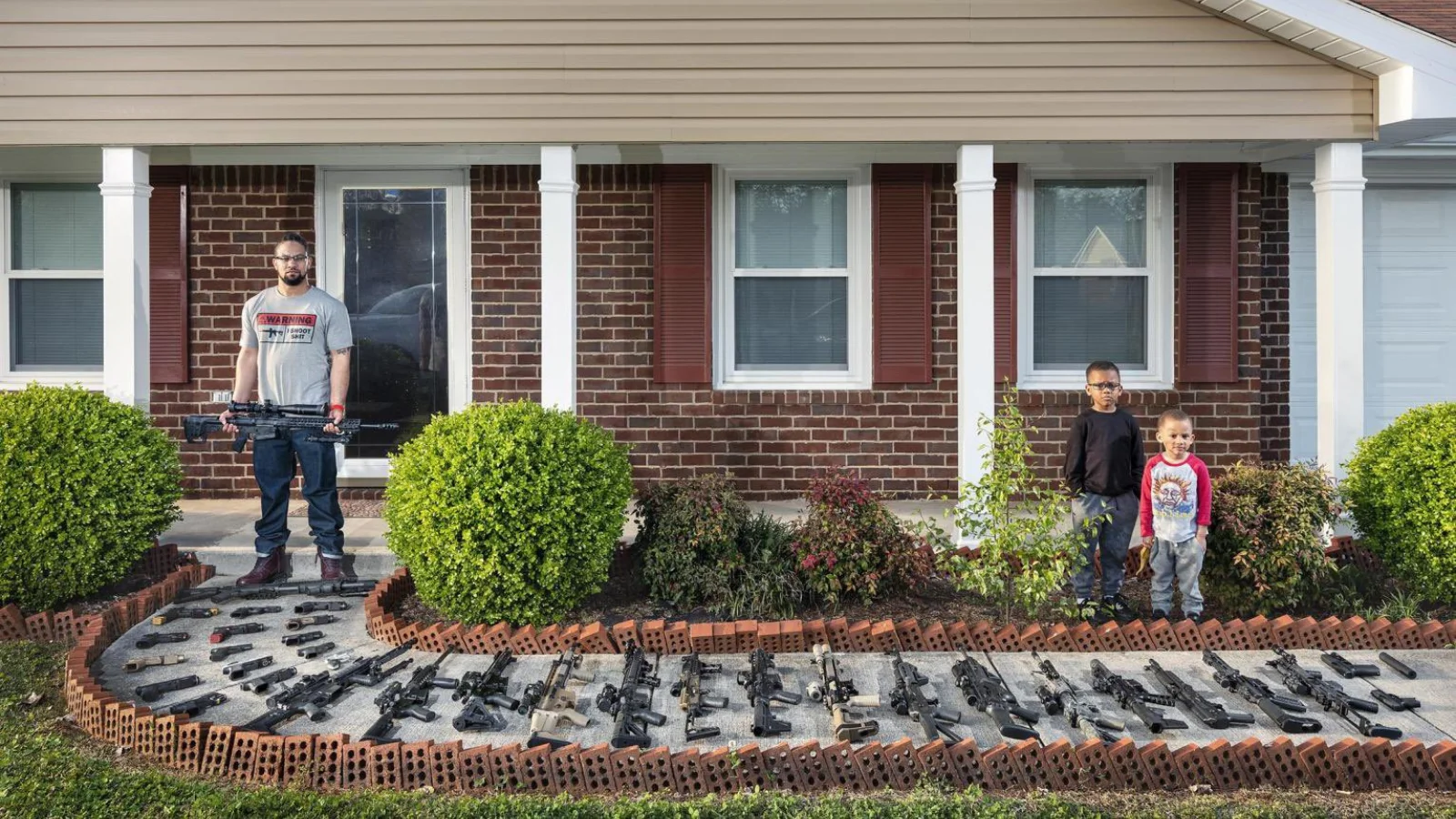 Brandon Brown con sus hijos Ashtan (5) y Carson (3) y sus armas frente a su casa.