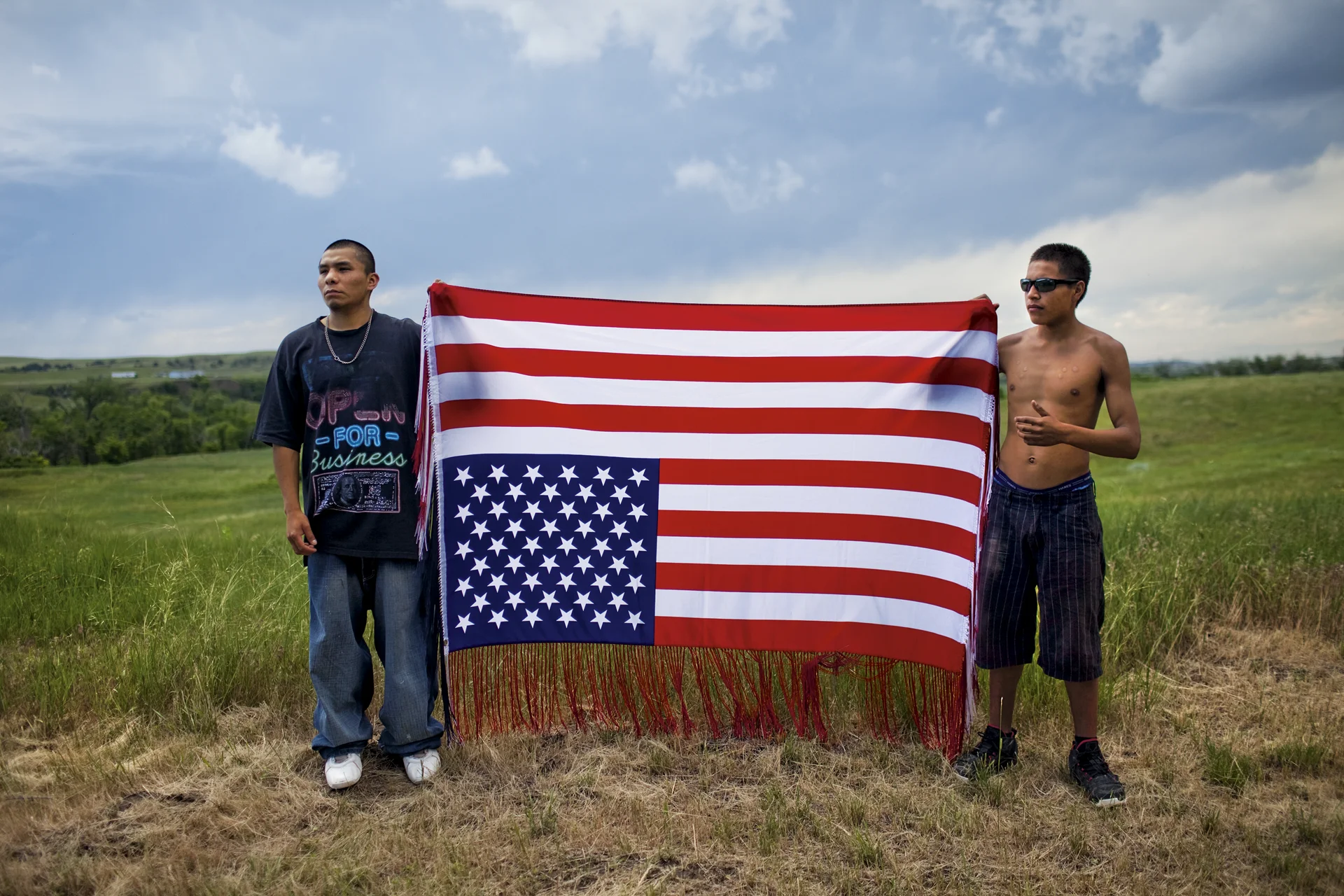 Los jóvenes oglala sostienen una bandera al revés, un símbolo internacional de angustia y un acto de desafío hacia el gobierno de los EE. UU., en una manifestación para conmemorar un tiroteo de 1975.