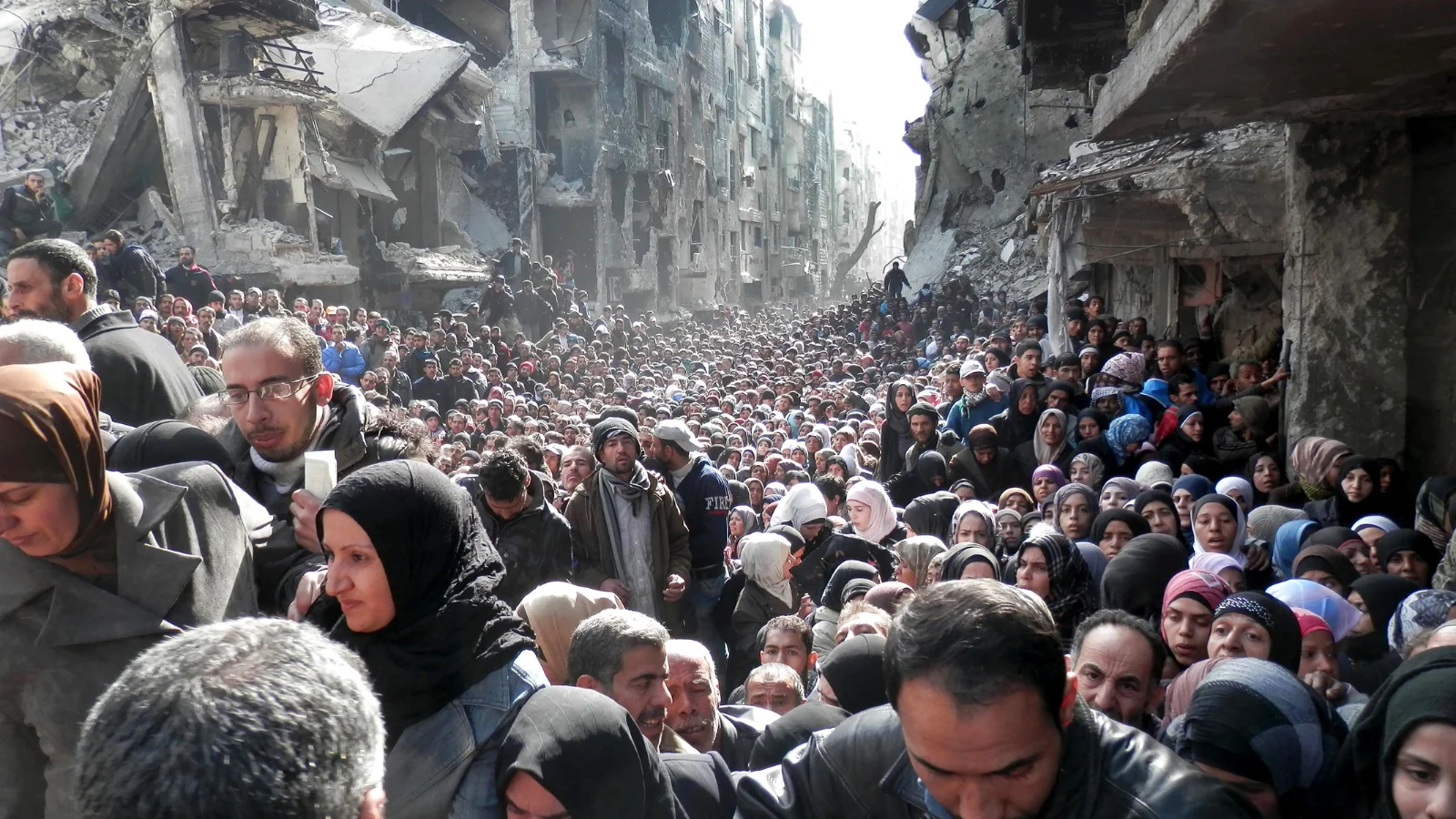 Residentes de Yarmouk, un barrio de palestinos en Siria, haciendo fila para recibir alimentos.