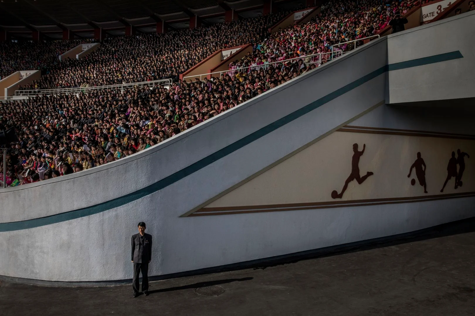 Una multitud espera el inicio de la maratón de Pyongyang en el estadio Kim Il-sung, mientras que un oficial vigila la salida.