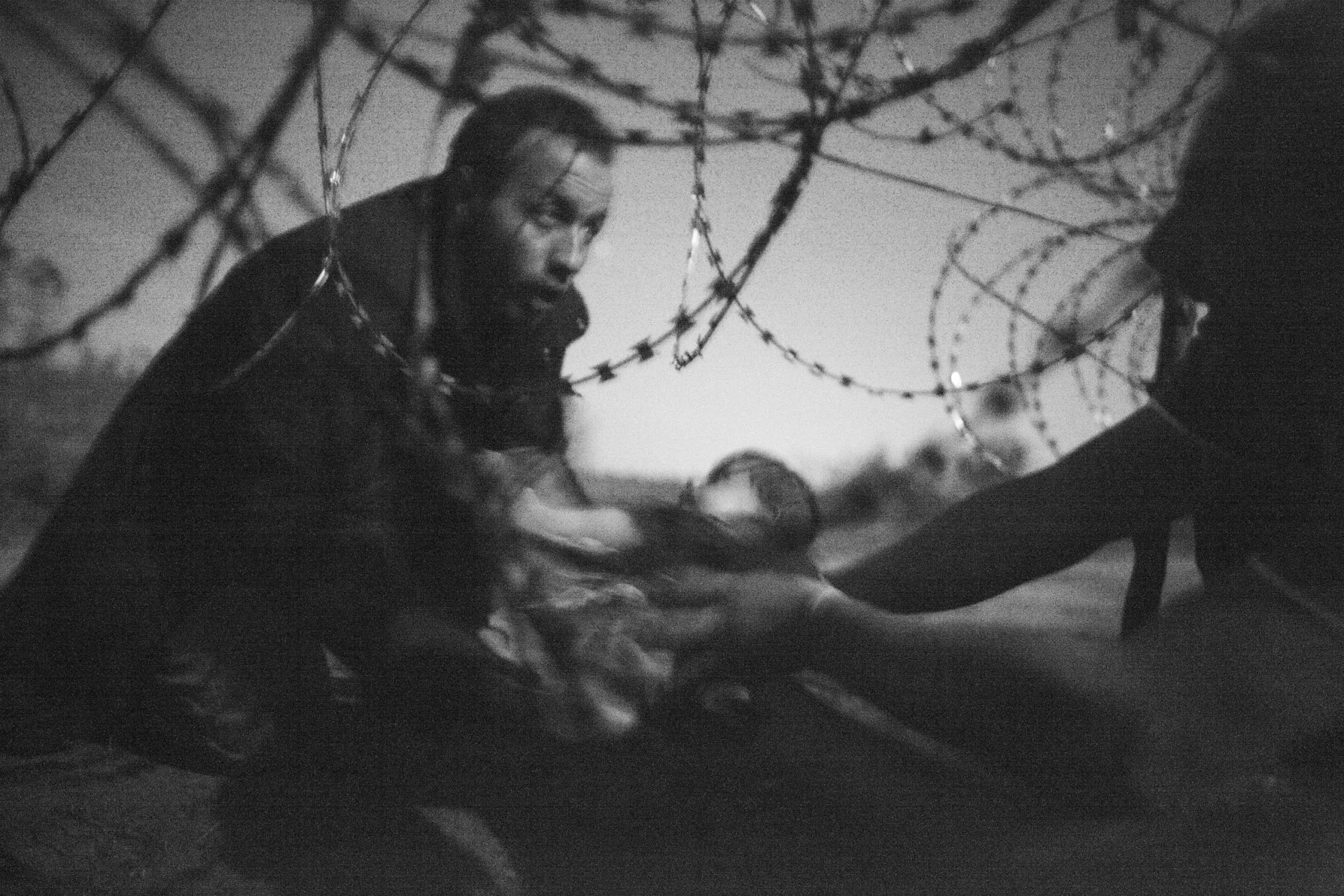 Un bebé es entregado a través de un agujero en una barrera de alambre de púas a un refugiado sirio que ya logró cruzar la frontera de Serbia a Hungría, cerca de Röszke.