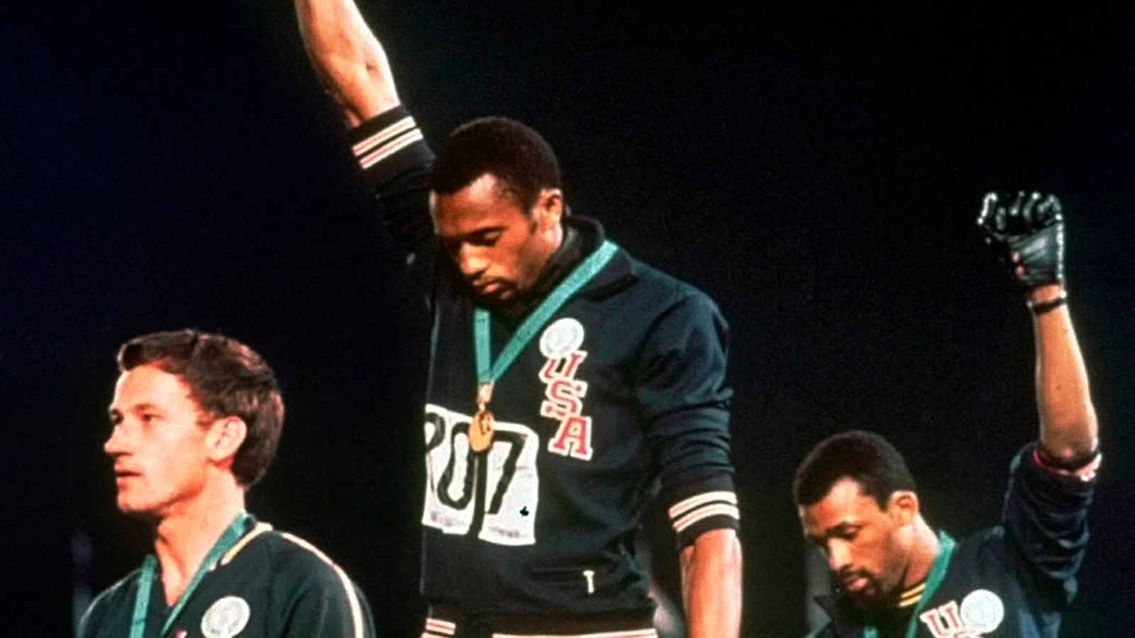 Los atletas afroamericanos Tommie Smith y John Carlos, medalla de oro y de bronce en los Juegos Olímpico, alzando su puño envuelto en un guante negro mientras el himno estadounidense es entonado.